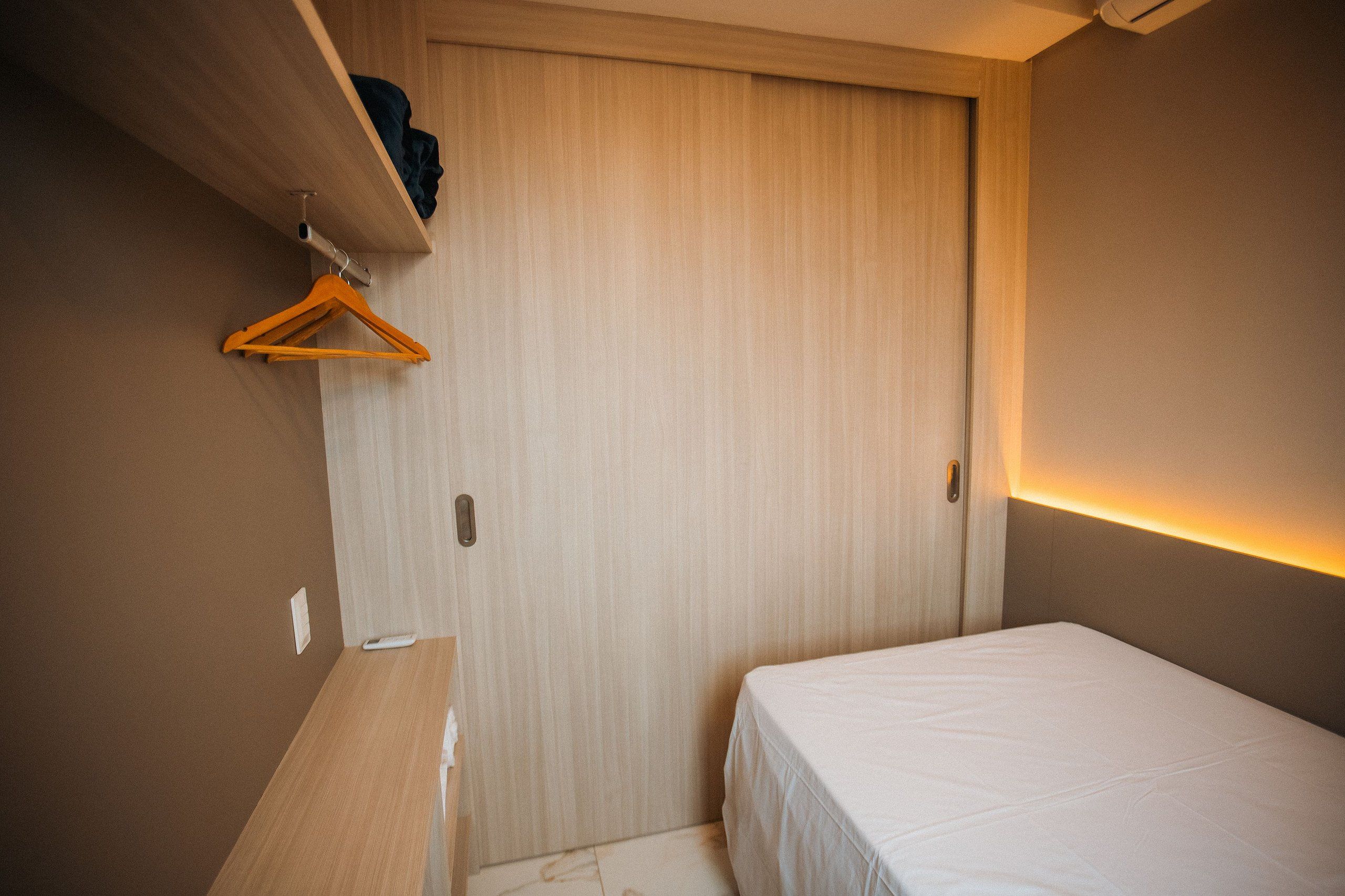 Un dormitorio pequeño y ordenado con una cama individual, un escritorio de madera y un armario.