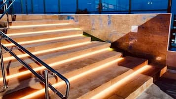 Un conjunto de escalones exteriores con barandillas metálicas que conducen a un nivel superior con una barrera de cristal.