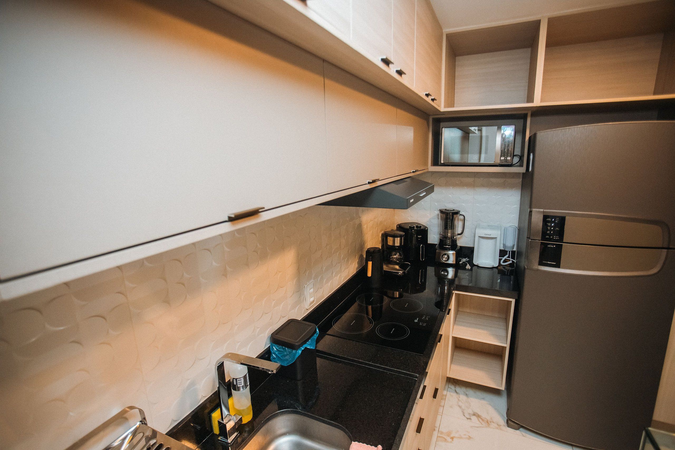 Una cocina compacta equipada con microondas, estufa y refrigerador.