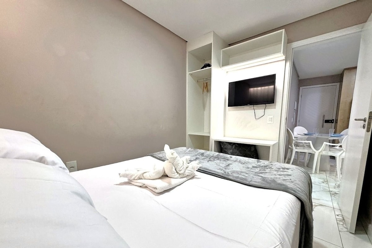 A hotel room with a bed, a television, a desk, and a chair.