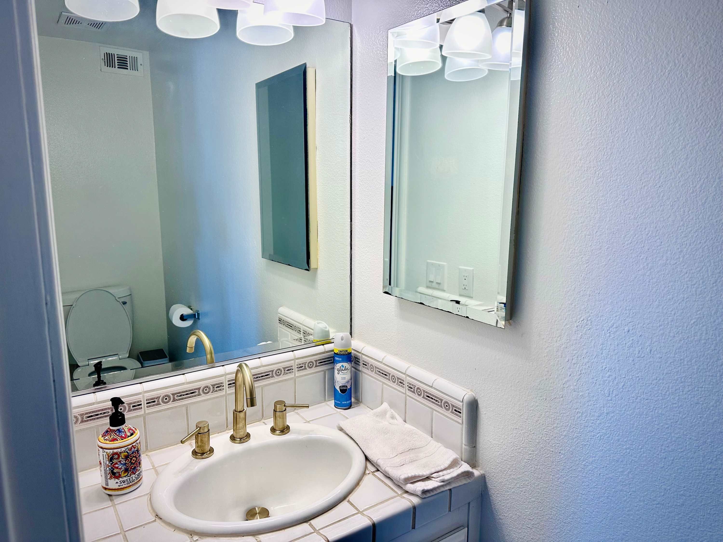 Une salle de bain avec un lavabo blanc, un miroir et des toilettes.