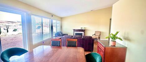 A dining area with a wooden table and chairs, a sofa, and a fireplace.
