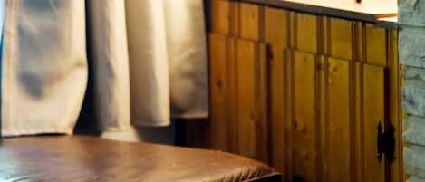 A room with a wooden bench, a lamp with a decorative base, and a wooden cabinet.
