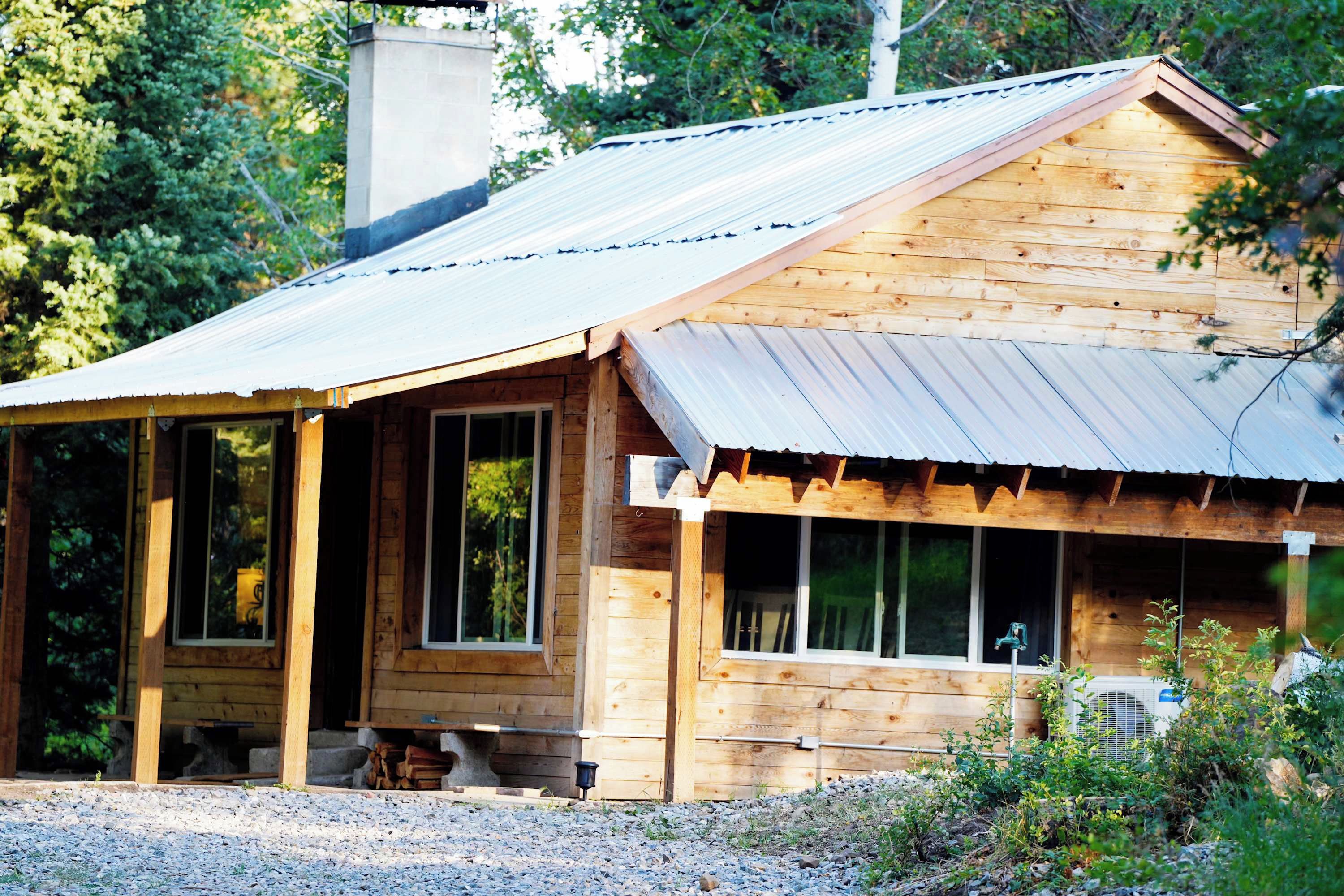 Une cabane en bois avec un toit en métal, de grandes fenêtres et une véranda.