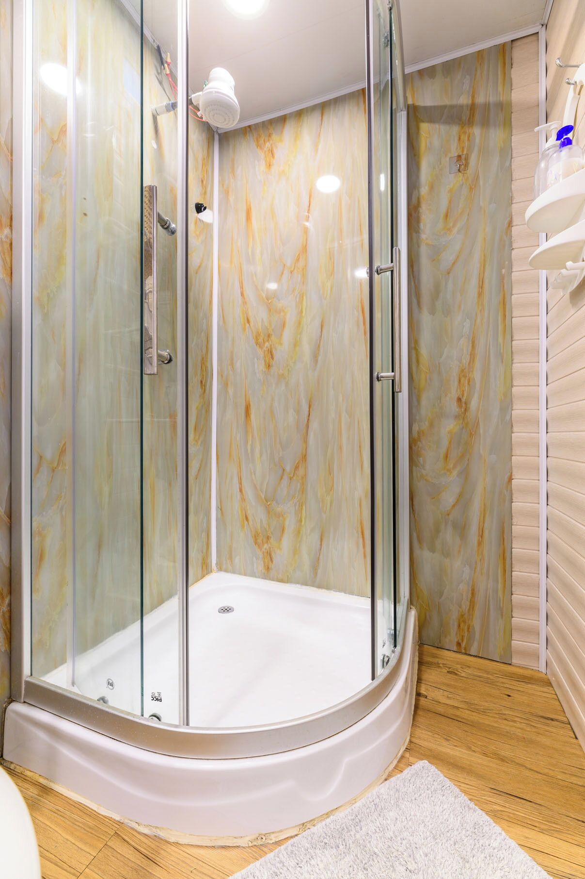 Une salle de bain moderne avec une douche en verre, des murs en marbre et un plancher en bois.