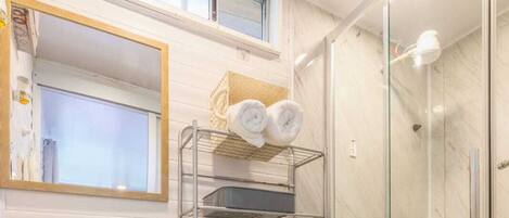A modern bathroom with a pedestal sink, toilet, and a glass-enclosed shower.