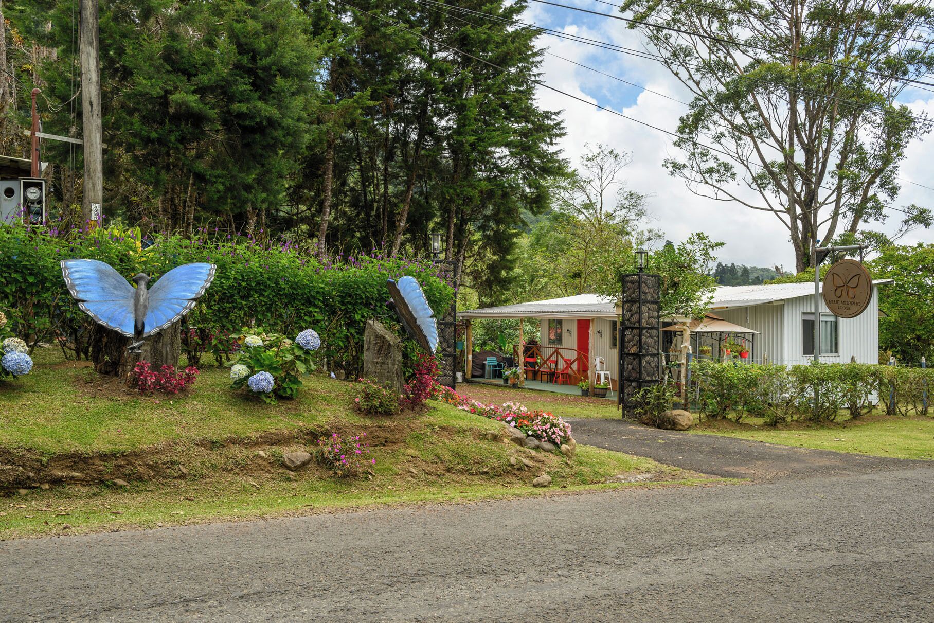 A lodge with a small building, a covered outdoor seating area, and a butterfly sculpture.