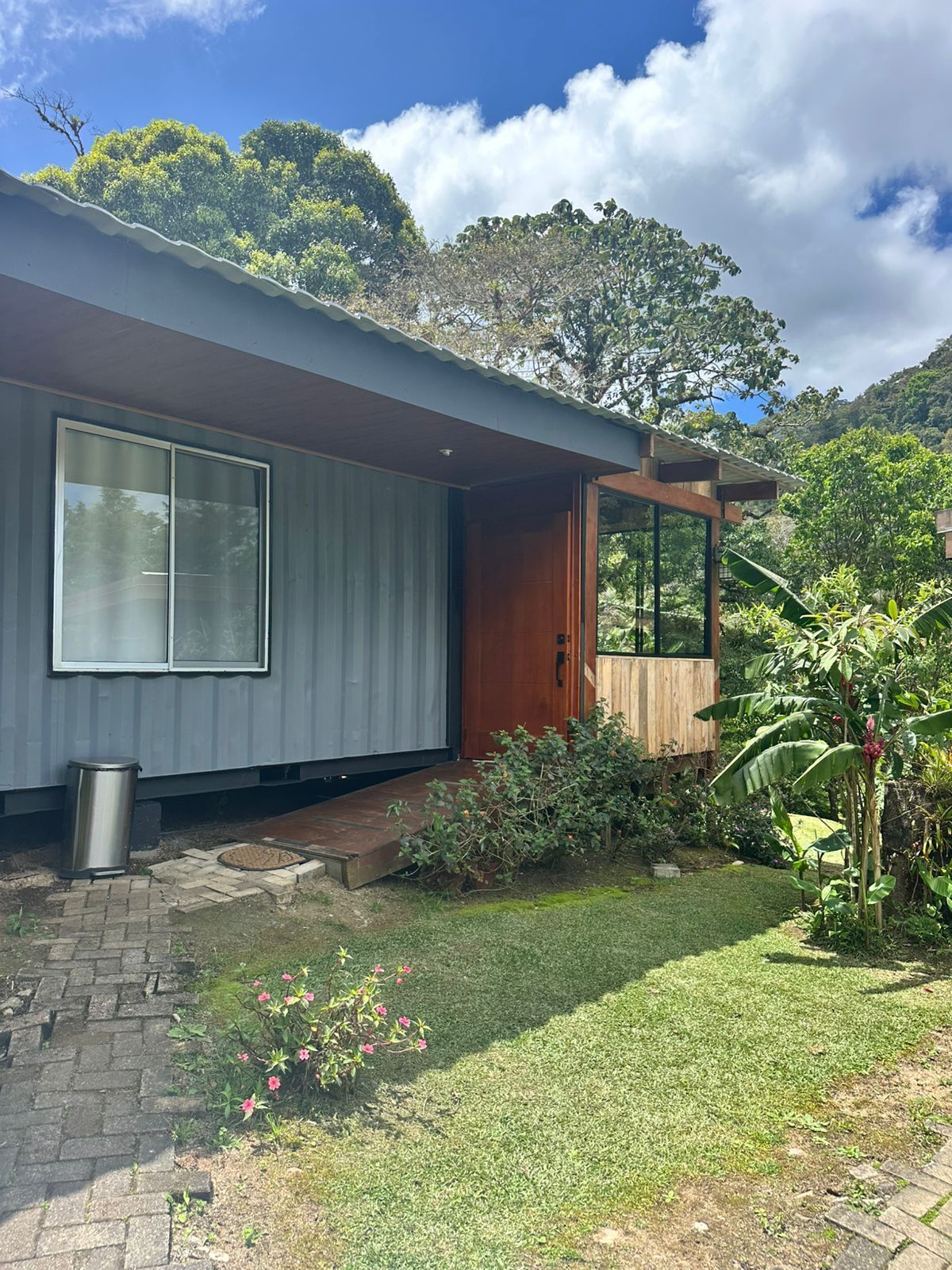 Una casa moderna con un ventanal grande, una puerta de madera y un porche pequeño.
