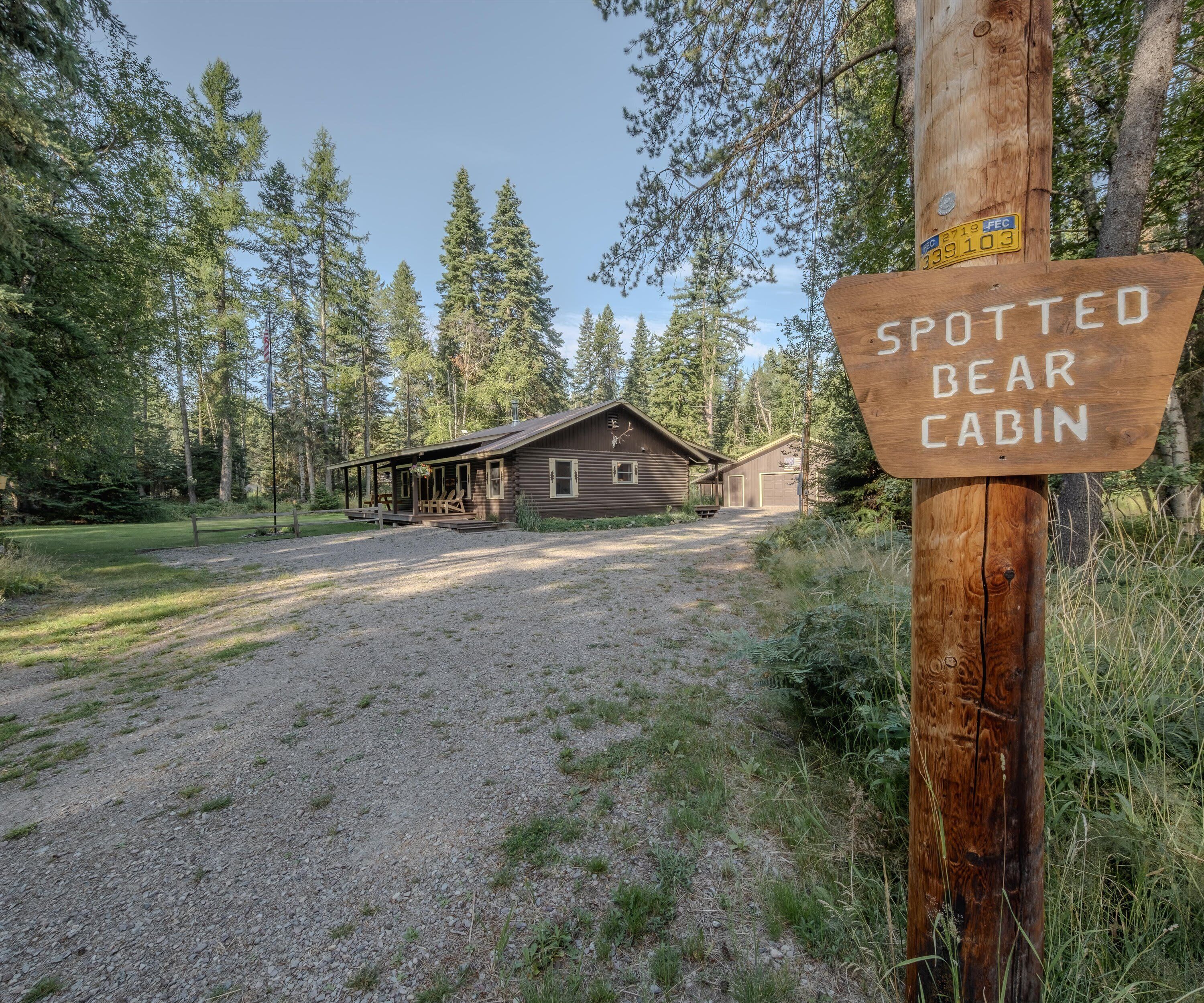 A cabin labeled "Spotted Bear Cabin" with a gravel driveway leading to it, surrounded by tall trees.