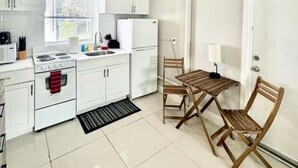 A kitchen with white cabinets, a stove, a sink, and a ceiling fan.