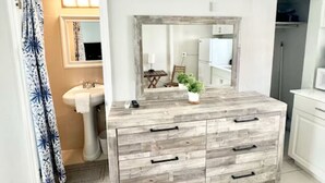 A modern bathroom with a wooden vanity, a sink, and a mirror.