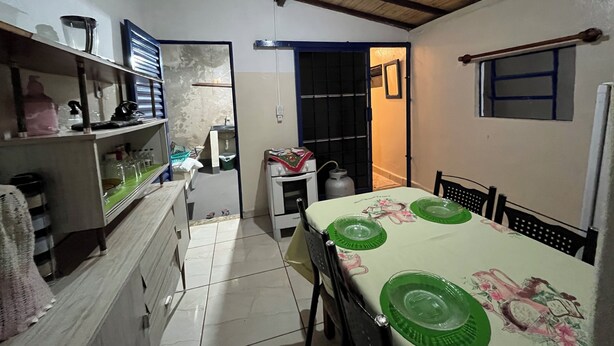 A compact kitchen with a dining area, featuring a tiled floor, a wooden ceiling, and basic amenities like a sink and a gas stove. - New Space - Grandma Dudu's Accommodations (Olímpia)