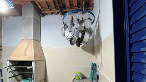 A compact kitchen with a wood-beamed ceiling, a built-in oven, and hanging pots. - New Space - Grandma Dudu's Accommodations (Olímpia)