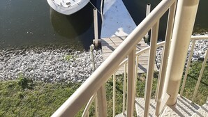 A marina with boats docked, a wooden dock, and a building with balconies in the background. - C&D REST-A-WHILE Book 2 Nights 3rd Is Free 9-1-26 to 9-27-26 Stays Only (Oak Harbor)