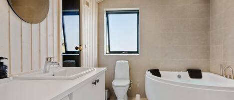 A modern bathroom with a freestanding bathtub, a toilet, and a sink.