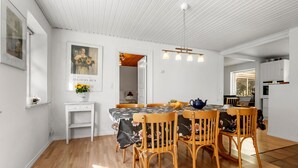 Un comedor con una mesa y sillas de madera, un jarrón con flores y un cuadro en la pared.