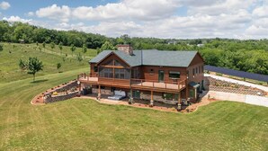 A large, two-story wooden house with a deck, surrounded by a well-maintained lawn and trees. - Main Selah Hills Ranch (Agency)