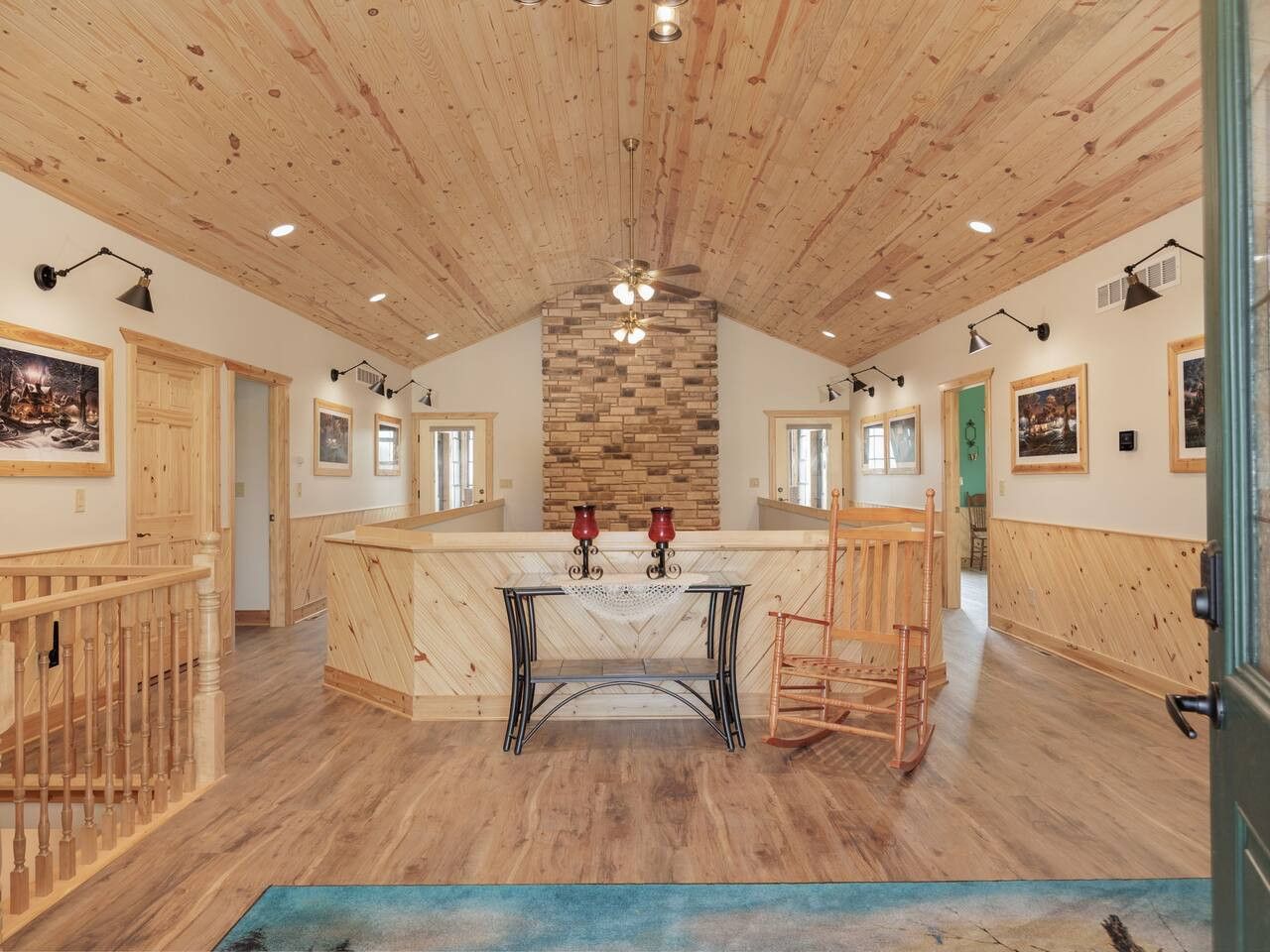 Een ruime kamer met een hoog houten plafond, een centraal gelegen stenen openhaard en een grote houten eettafel met stoelen.