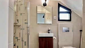 A modern bathroom with a glass shower enclosure, a wooden vanity, a toilet, and a small window. - Carioquinha Studio - Aveiro city center (Aveiro)