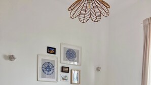 A neatly made bed with a white and beige duvet, two orange pillows, and a brown throw blanket. There are two bedside tables with lamps, a wall-mounted light fixture, and framed pictures on the wall. - Carioquinha Studio - Aveiro city center (Aveiro)