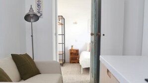 A narrow hallway with a white sofa, a small table, and a cabinet. - Carioquinha Studio - Aveiro city center (Aveiro)