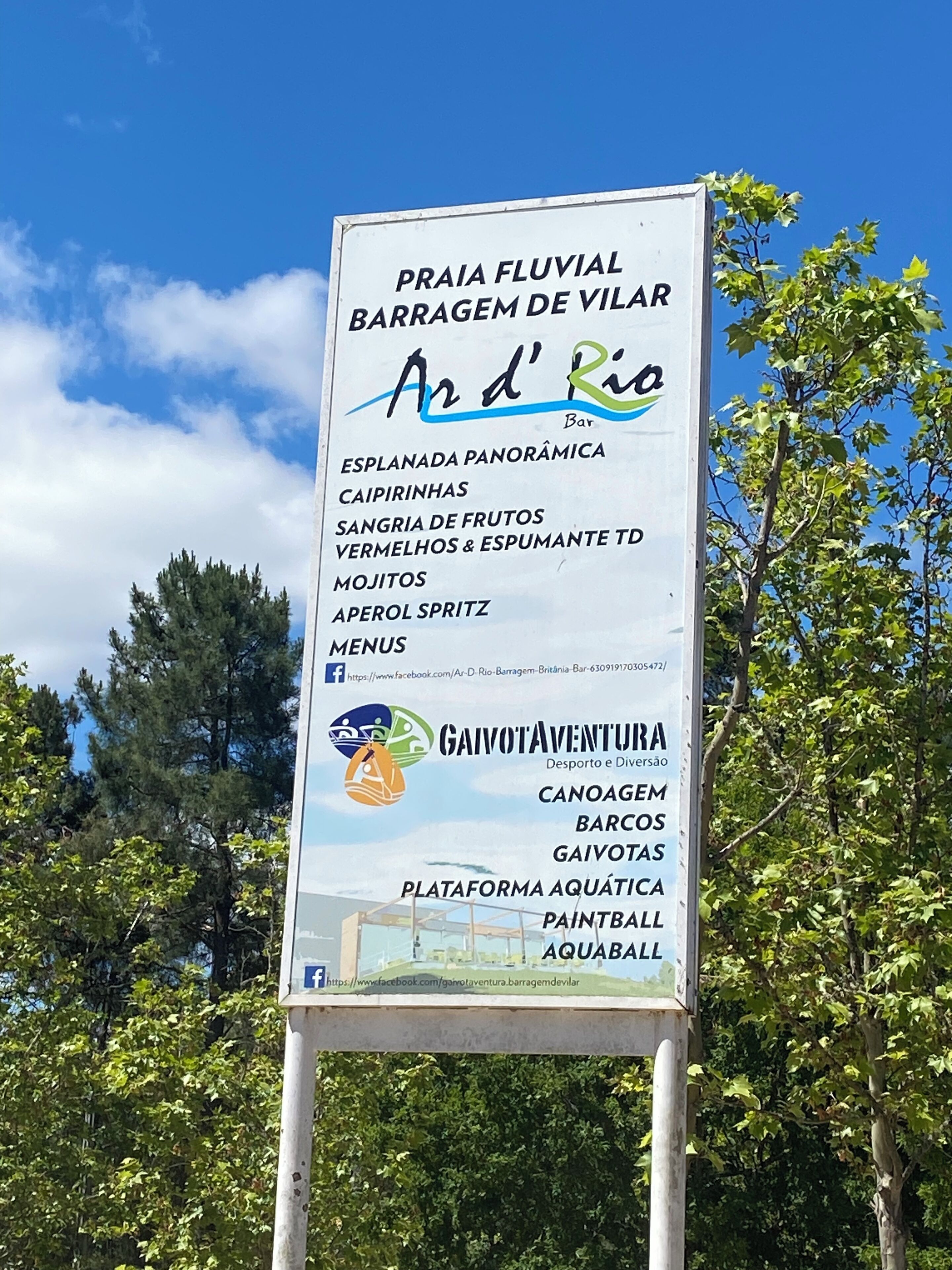 Un panneau indiquant les différents services proposés, notamment une vue panoramique, des caïpirinhas, de la sangria aux fruits, du vin rouge et du vin mousseux, des mojitos et des apérol spritz.