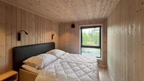 A bedroom with a bed, wooden walls, a window, and a nightstand. - Awesome home in Gålå with sauna (Gålå)