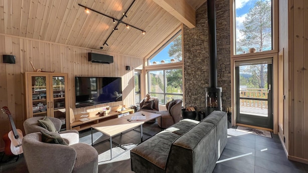 A cozy living room with a large TV, wooden furniture, and a stone fireplace. - Awesome home in Gålå with sauna (Gålå)
