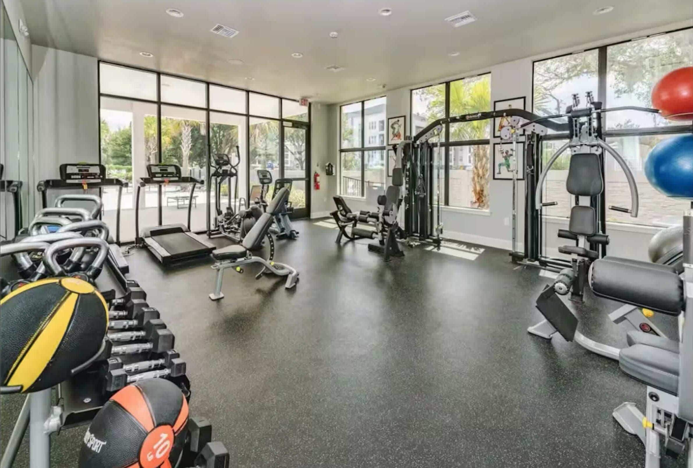 Een fitnessruimte met loopbanden, gewichtmachines en fitnessballen.