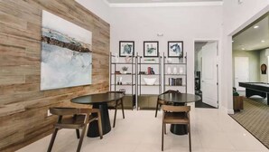 A modern dining area with a wooden accent wall, a large abstract painting, and a black dining table with wooden chairs. - Chic Villa Domani Retreat 9ppl (Davenport)