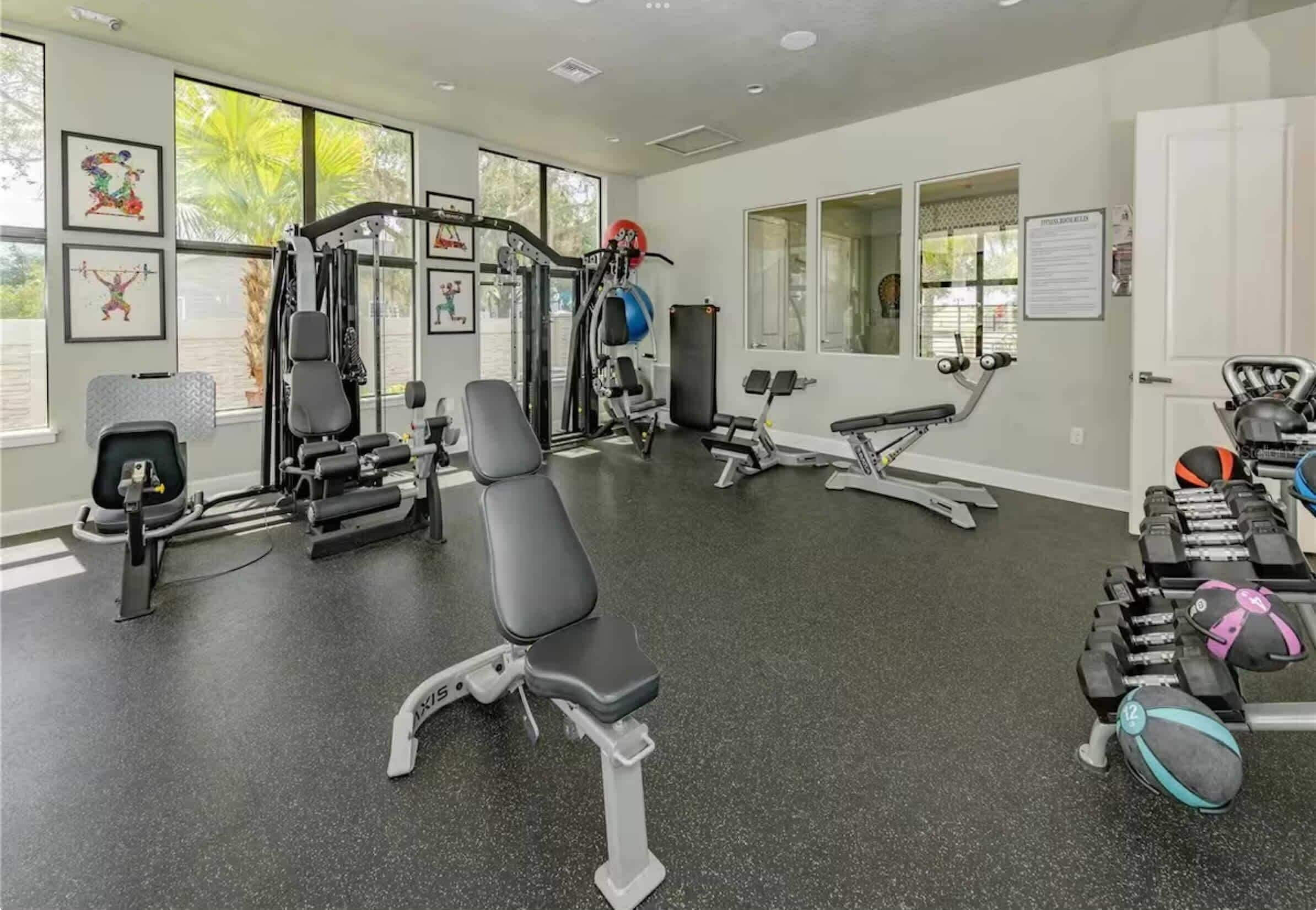 A gym with various exercise equipment, including a bench, weight machines, and dumbbells.