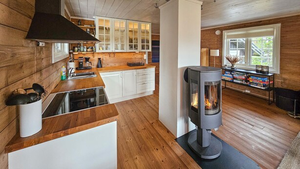 Une cuisine moderne avec des meubles en bois, un îlot central et un poêle à bois.