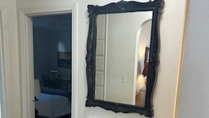 A bedroom with a bed, a bedside table, and a mirror on the wall. - Charming Lovely 1940s Bungalow (Ashland)