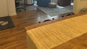 A wooden dining table with a textured table runner, a grey rug, and a pair of slippers on a doormat. - Charming Lovely 1940s Bungalow (Ashland)