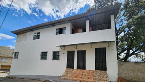 Un bâtiment à deux étages, de couleur blanche, portant le numéro 99, avec une base en pierre, de nombreuses fenêtres dot ées de barreaux métalliques et un toit plat.