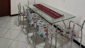 Un coin repas avec une table en verre, des chaises en métal et un chemin de table rouge.