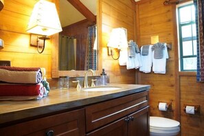Ein Badezimmer aus Holz mit Waschbecken, Spiegel und Handtuchhalter.