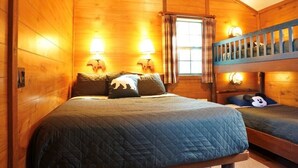 A wooden cabin bedroom with a bunk bed and two bedside lamps.