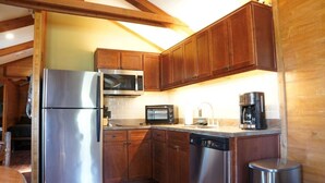 A compact kitchen with wooden cabinets, a stainless steel refrigerator, a microwave, a toaster, and a coffee maker.