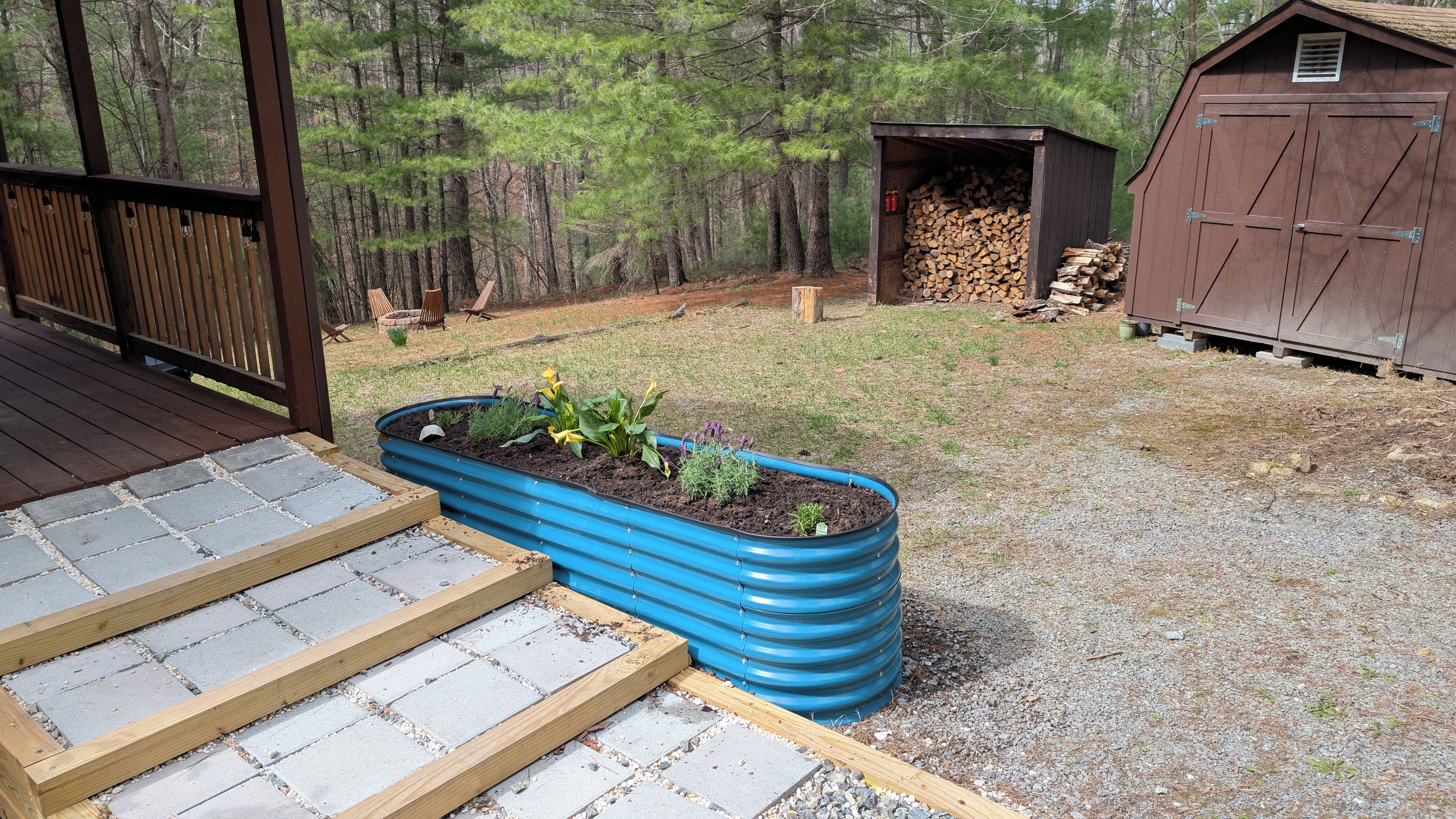 A garden with raised beds, a wooden deck, and a shed.