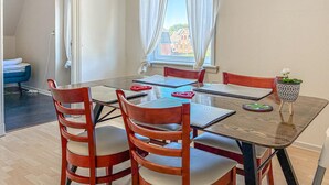 A dining area with a table, chairs, and a view of buildings outside. - Cozy apartment in Højer with WiFi (Højer)