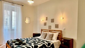 A bedroom with a wooden bed, a green chair, and a nightstand. - Cobalt - Casa do Parque (Aveiro)