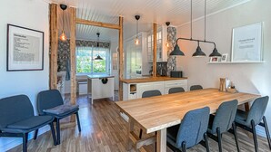 A modern kitchen with wooden cabinets, a dining area with a wooden table and chairs, and pendant lighting. - Nice home in Värnamo with sauna (Värnamo)