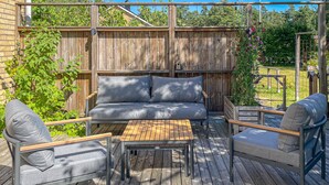 An outdoor deck with a wooden bench, two chairs, and a small table. - Nice home in Värnamo with sauna (Värnamo)