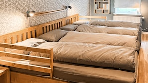 A wooden bunk bed with a headboard, a bedside table, and a wall-mounted lamp. - Nice home in Värnamo with sauna (Värnamo)