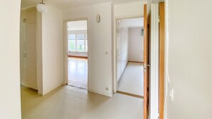 A hallway with a light-colored floor, a ceiling fan, and a door leading to another room. - Beautiful apartment in Pauliström (Pauliström)