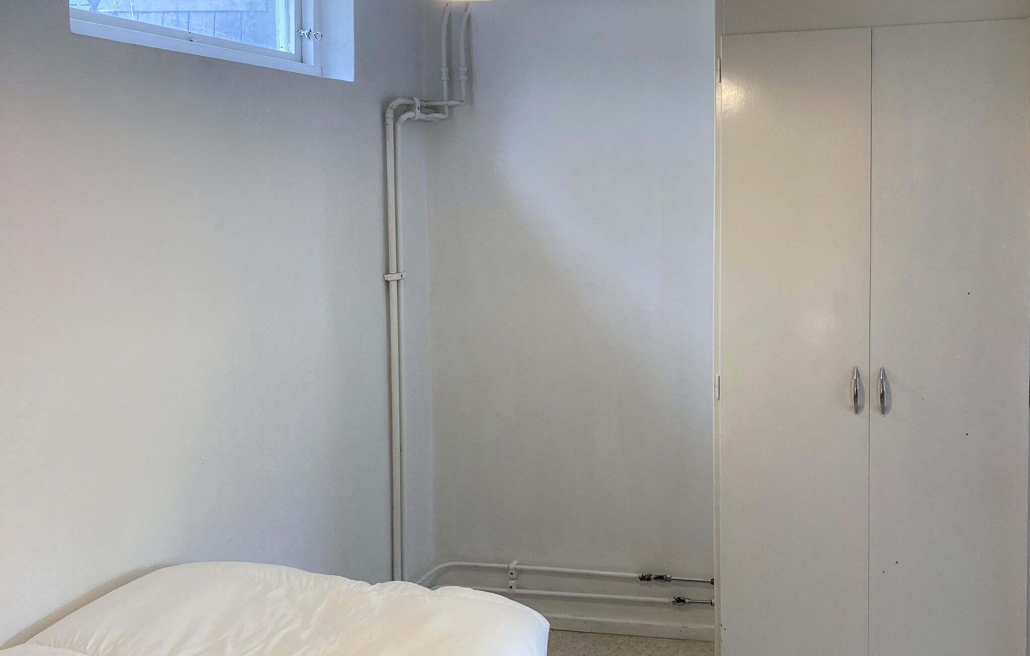 Une chambre avec un lit, une armoire et une fenêtre.