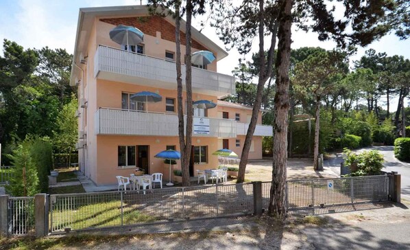 A multi-story hotel with balconies, outdoor seating, and a fenced garden area.