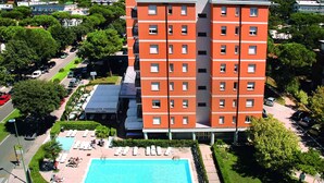 A multi-story hotel with a swimming pool and outdoor seating area.