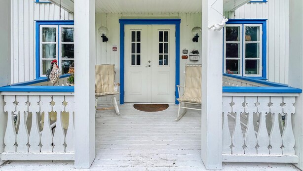 A white building with blue trim and a porch with two rocking chairs. - Beautiful home in Gunnarsbytorp with sauna (Gunnarsbytorp)